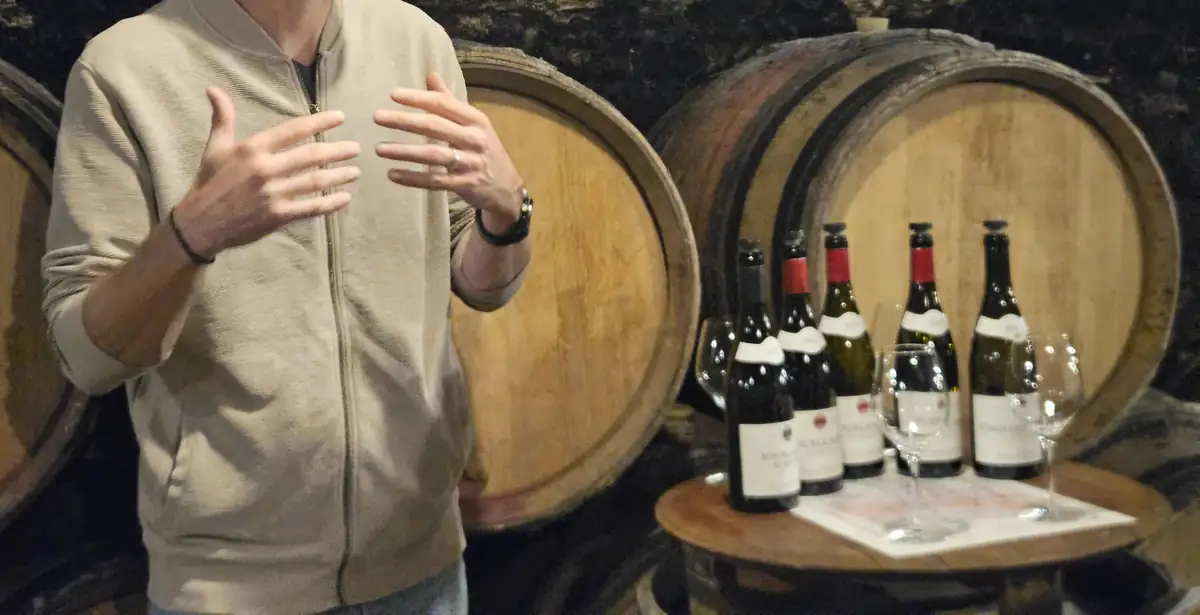 A winemaker talking about his wines in front of the barrels