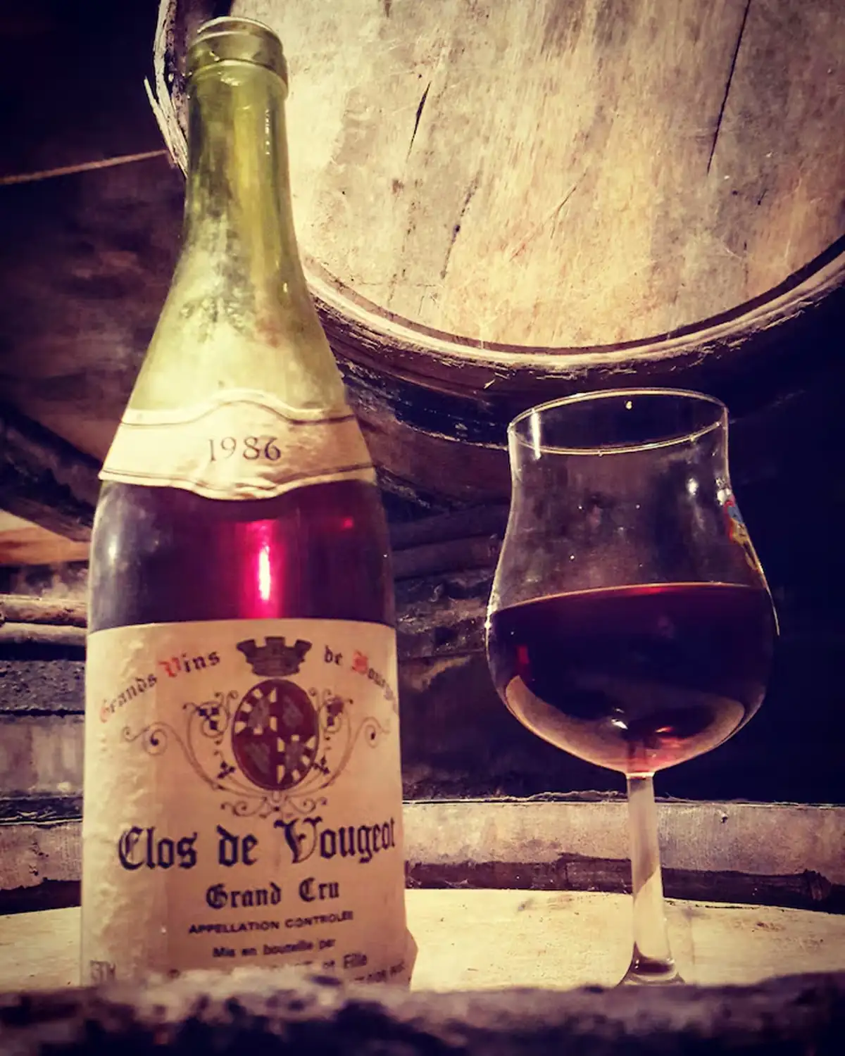 A bottle of Clos de Vougeot Grand Cru and a glass of red wine in the cellar